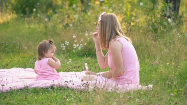 Mama i córka siedzą na trawniku — Wideo stockowe