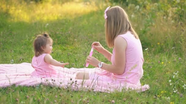 Mom and daughter are sitting on the lawn — Stock Video