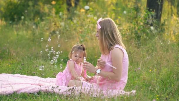 Mãe e filha estão sentados no gramado — Vídeo de Stock