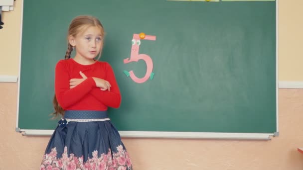The girl is standing near the blackboard — Stock Video