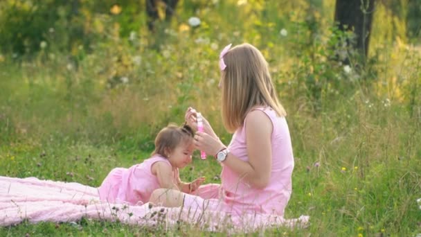 Mutter und Tochter sitzen auf dem Rasen — Stockvideo