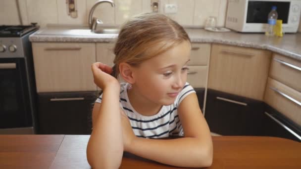 Маленькая девочка сидит за столом — стоковое видео