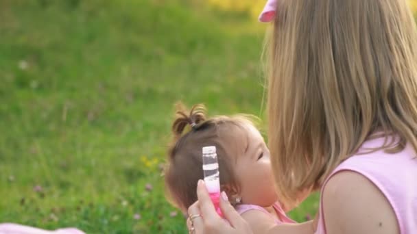 Mãe e filha estão sentados no gramado — Vídeo de Stock