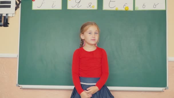A menina está de pé perto do quadro negro — Vídeo de Stock