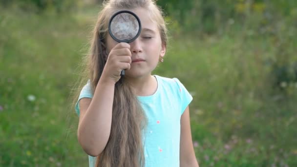 Маленькая девочка смотрит сквозь лупу — стоковое видео