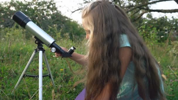 Niña está mirando a través de un telescopio — Vídeo de stock