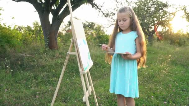 Маленькая девочка рисует на природе — стоковое видео