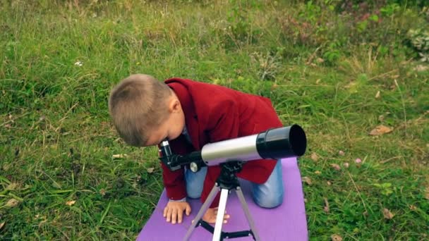 Niño con un telescopio en la naturaleza — Vídeo de stock