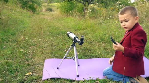 Menino com um telescópio na natureza — Vídeo de Stock