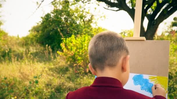 Мальчик рисует на природе — стоковое видео