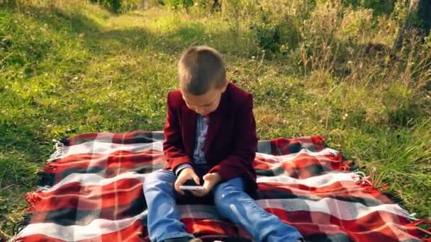 Niño jugando en el teléfono en los juegos — Vídeos de Stock