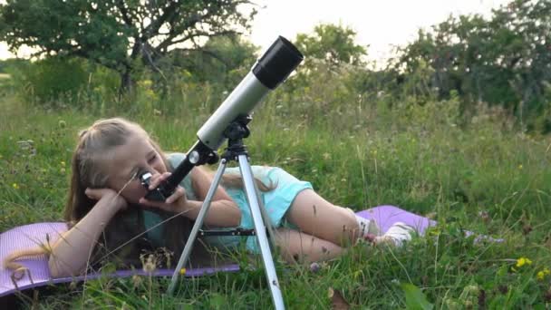 Bambina sta guardando attraverso un telescopio — Video Stock