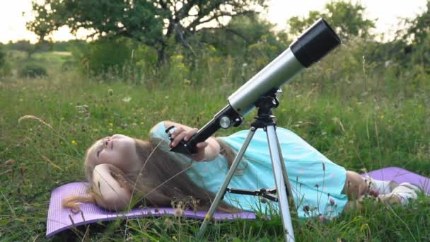 Petite fille regarde à travers un télescope — Video