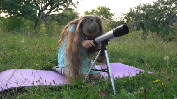 Bambina sta guardando attraverso un telescopio — Video Stock