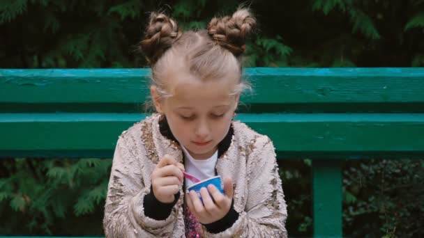 Mädchen Isst Eis Sitzend Auf Einer Bank — Stockvideo