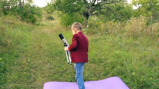 Niño con un telescopio en la naturaleza — Vídeo de stock