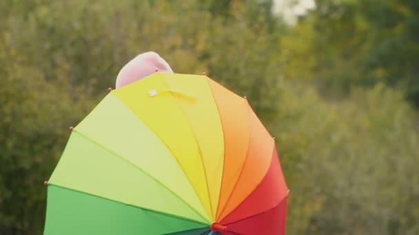 Kleines Mädchen spielt mit einem bunten Regenschirm — Stockvideo