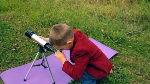 Niño con un telescopio en la naturaleza — Vídeo de stock