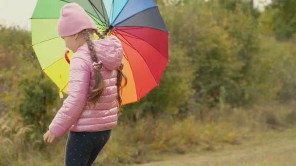 Маленькая девочка играет с разноцветным зонтиком — стоковое видео