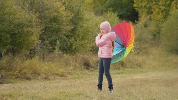 Маленькая девочка играет с разноцветным зонтиком — стоковое видео