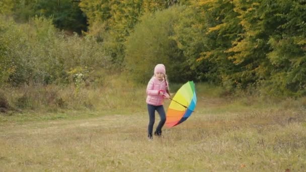 Little girl playing with a multi-colored umbrella — Stock Video