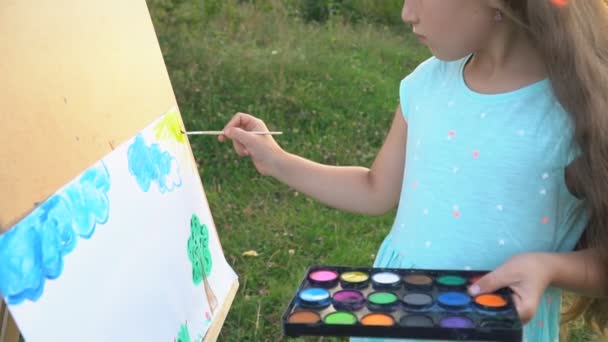Маленькая девочка рисует на природе — стоковое видео