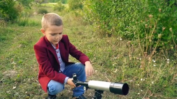 Niño con un telescopio en la naturaleza — Vídeo de stock