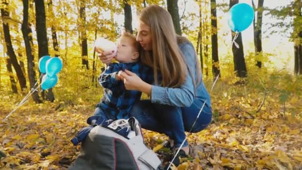 母亲在秋天的森林里用瓶子喂她的孩子 — 图库视频影像
