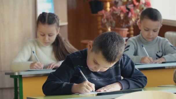 Діти пишуть, сидячи за столом — стокове відео