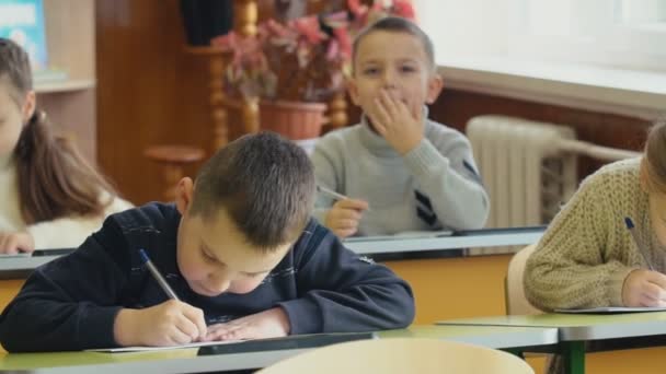 Дети пишут сидя за столом — стоковое видео