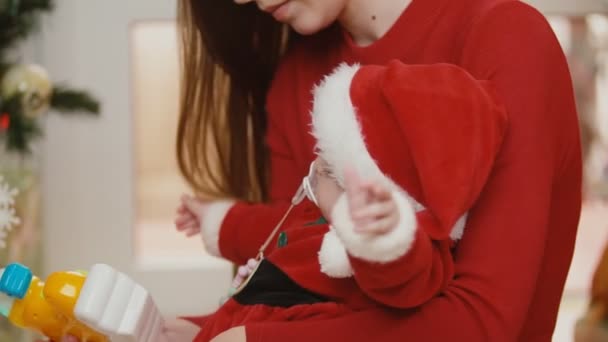 Mutter mit Baby neben dem Weihnachtsbaum — Stockvideo