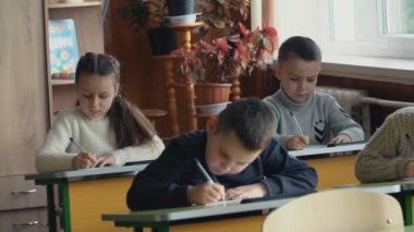 Okul masa başında otururken çocuklar yazmak