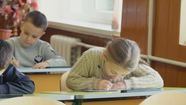 Children write sitting at a desk — Stock Video