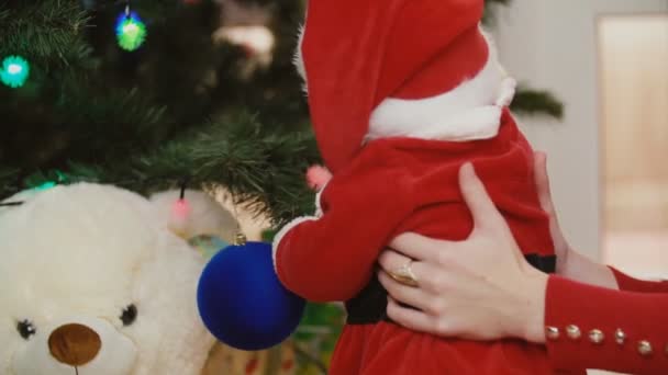 Mor med baby nära julgranen — Stockvideo