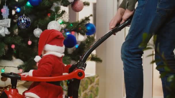 Uma menina em um terno de Papai Noel está rolando em carros de brinquedo — Vídeo de Stock