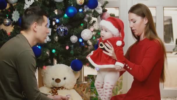 Familia sentada cerca del árbol de Navidad — Vídeo de stock