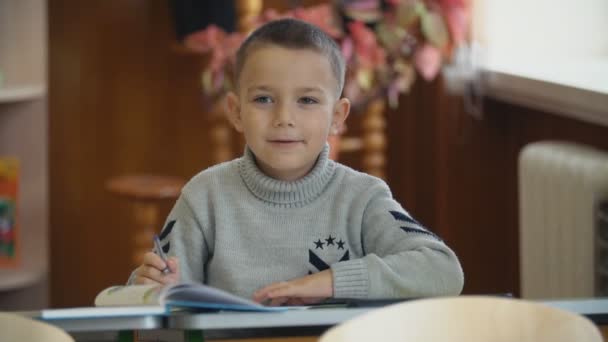 Dzieci pisać siedząc przy biurku — Wideo stockowe