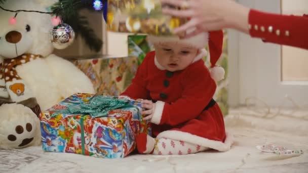 Mamma con bambino in costume da Babbo Natale guardando i regali — Video Stock