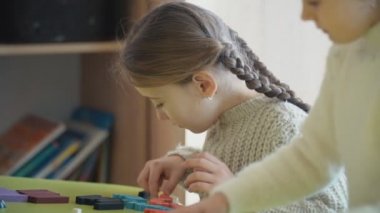 bir masada otururken bir tasarımcı ile oynayan kızlar