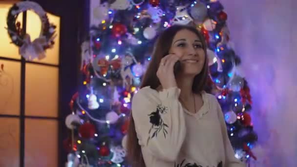 Menina falando ao telefone no fundo da árvore de Natal — Vídeo de Stock