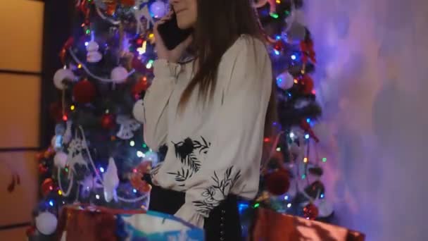 Dívka mluví po telefonu na pozadí vánoční stromeček — Stock video