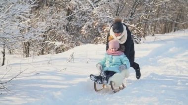 Anne kızı bir kızak üzerinde rulo.