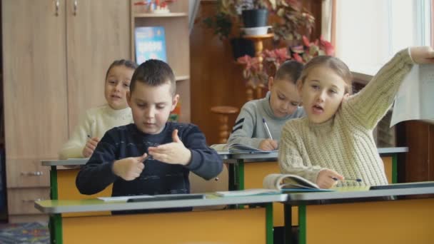 Los niños escriben sentados en un escritorio — Vídeos de Stock