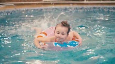 küçük kız havuzda yüzüyor.