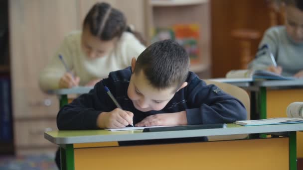 Anak-anak menulis sambil duduk di meja — Stok Video