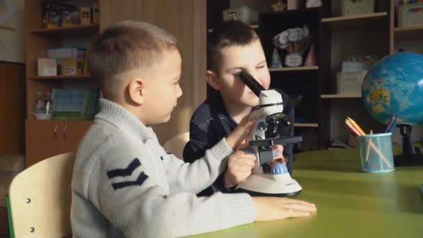 Мальчики смотрят на что-то в микроскопе — стоковое видео