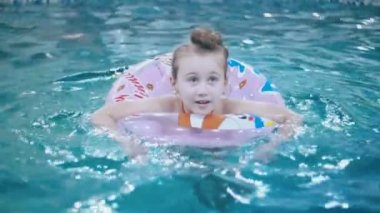 küçük kız havuzda yüzüyor.
