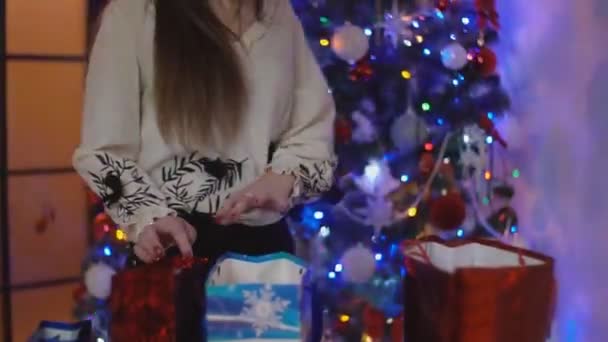Девушка смотрит в сумки с подарками — стоковое видео