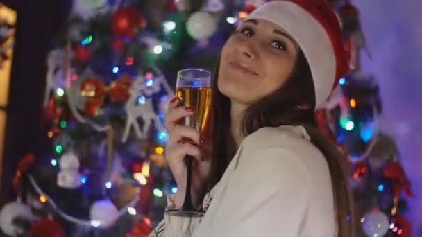 Девушка с бокалом шампанского на фоне рождественской елки — стоковое видео