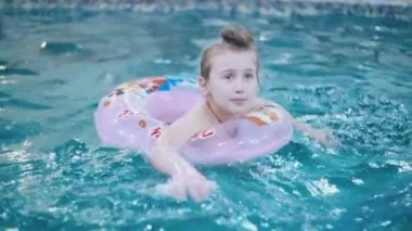 küçük kız havuzda yüzüyor.